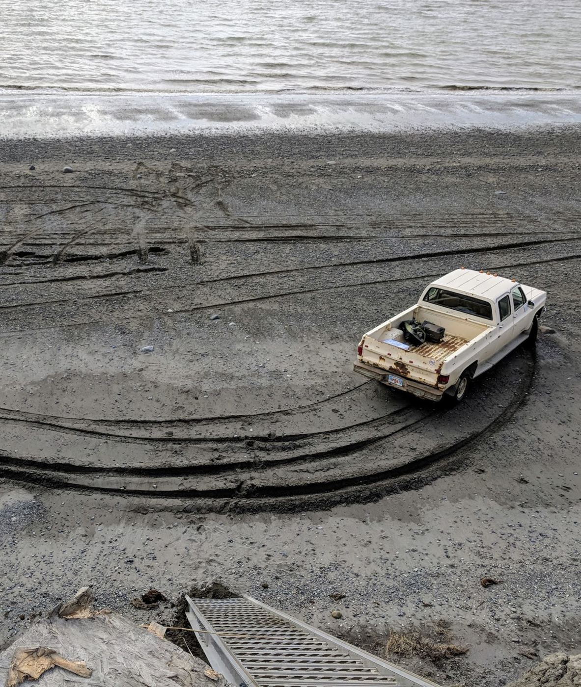 Looking down the bluff stairs at a pickup on the beach at low tide